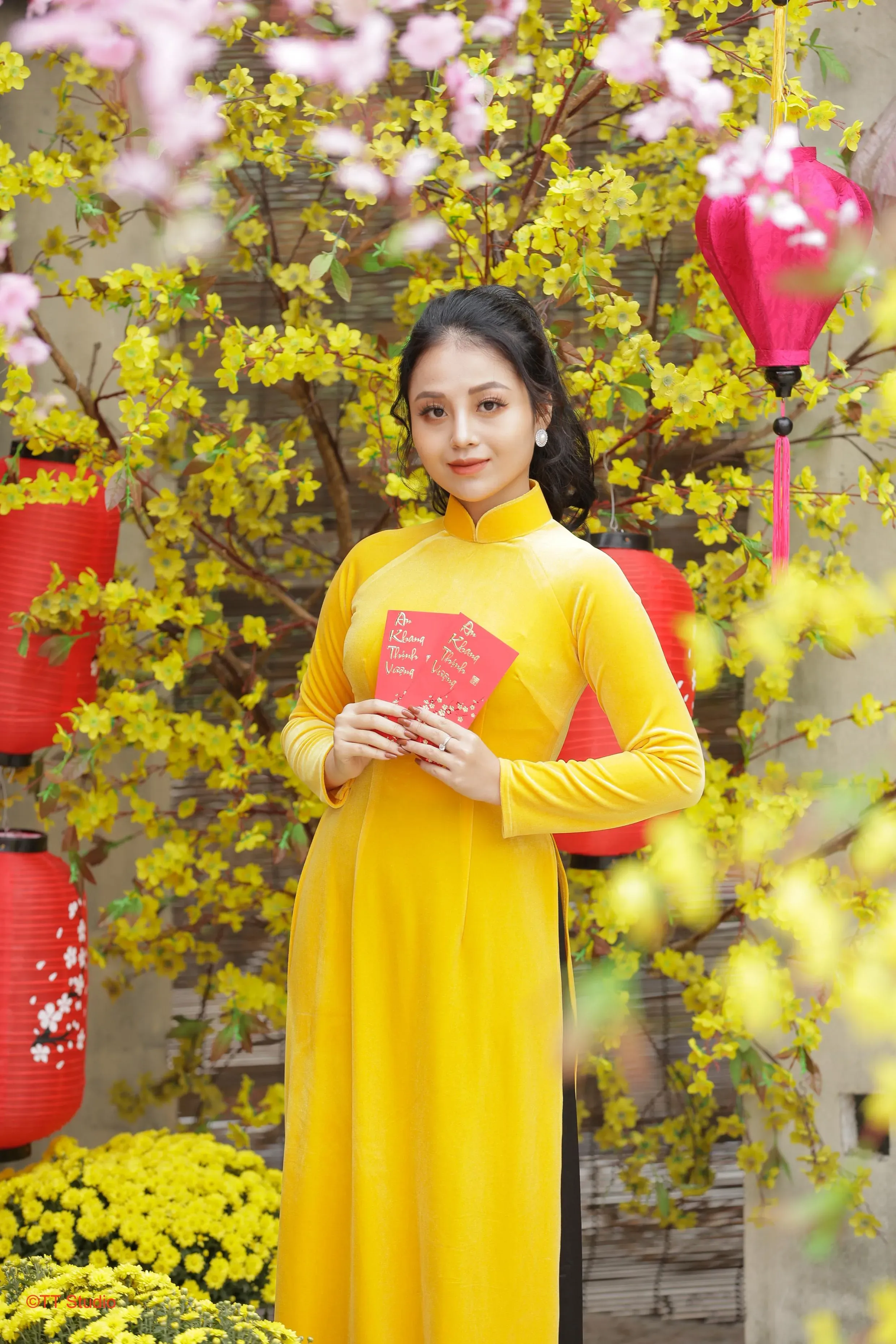 Chụp ảnh với áo dài tết và bao lì xì bên cây mai