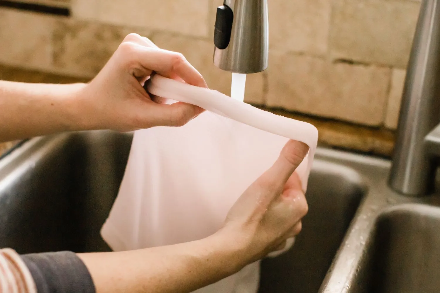 Bạn nên ngâm phần quần áo dính keo trong nước nóng để làm mềm vết bám