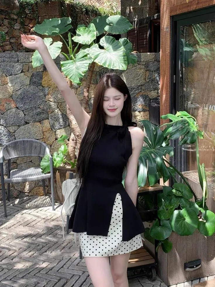 Outfit đen trắng nhẹ nhàng với áo sát nách cổ cao và chân váy chấm bi thanh lịch