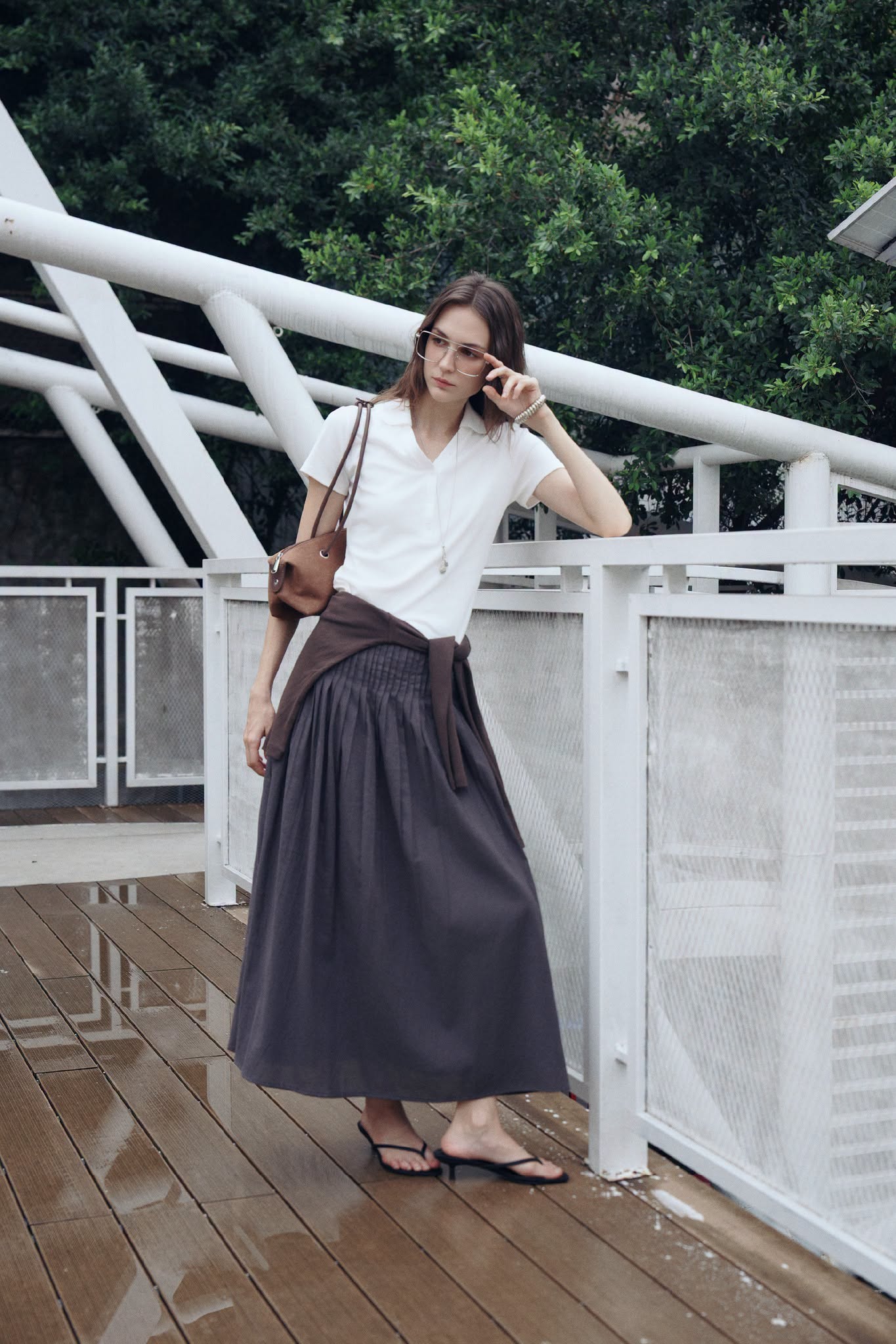 Nét nữ tính được thể hiện qua áo polo trắng, chân váy dài xếp ly và cardigan buộc ngang eo