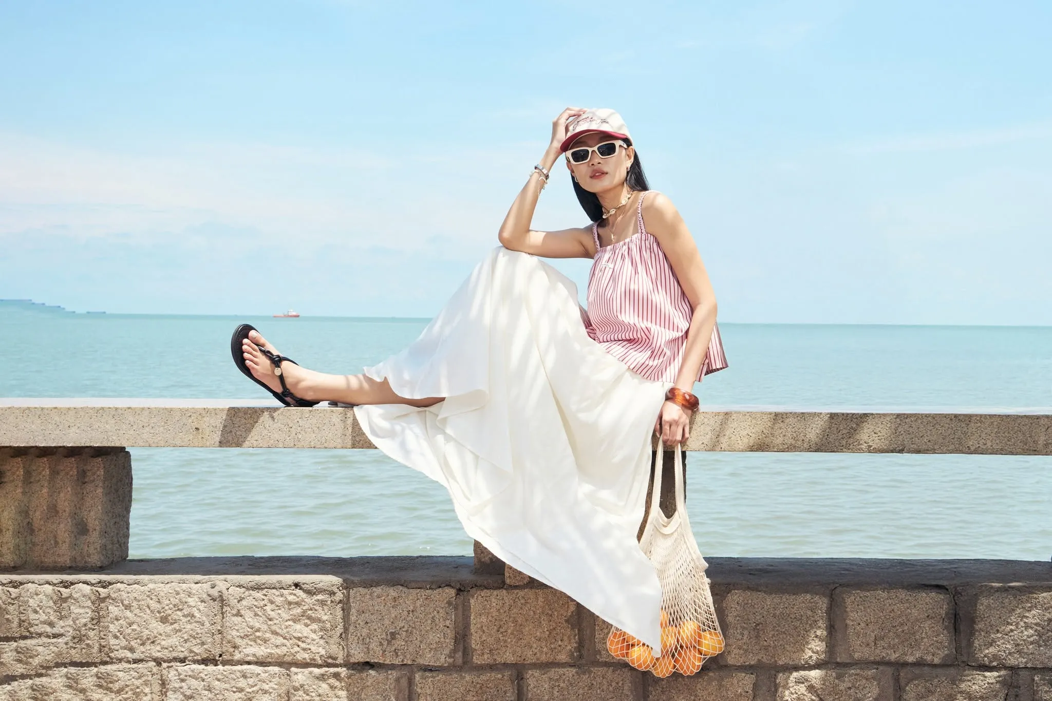 Sắc đỏ trắng nổi bật trên nền biển xanh khiến outfit lên hình sáng và đầy sức sống