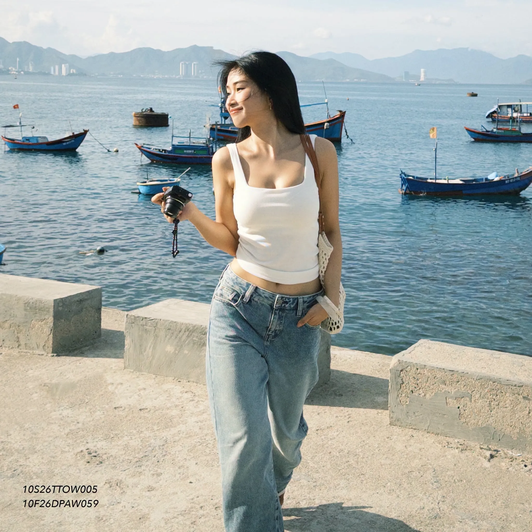 Áo tank top trắng và jeans ống rộng tạo phong cách phóng khoáng, hiện đại giữa khung cảnh biển Vĩnh Hy