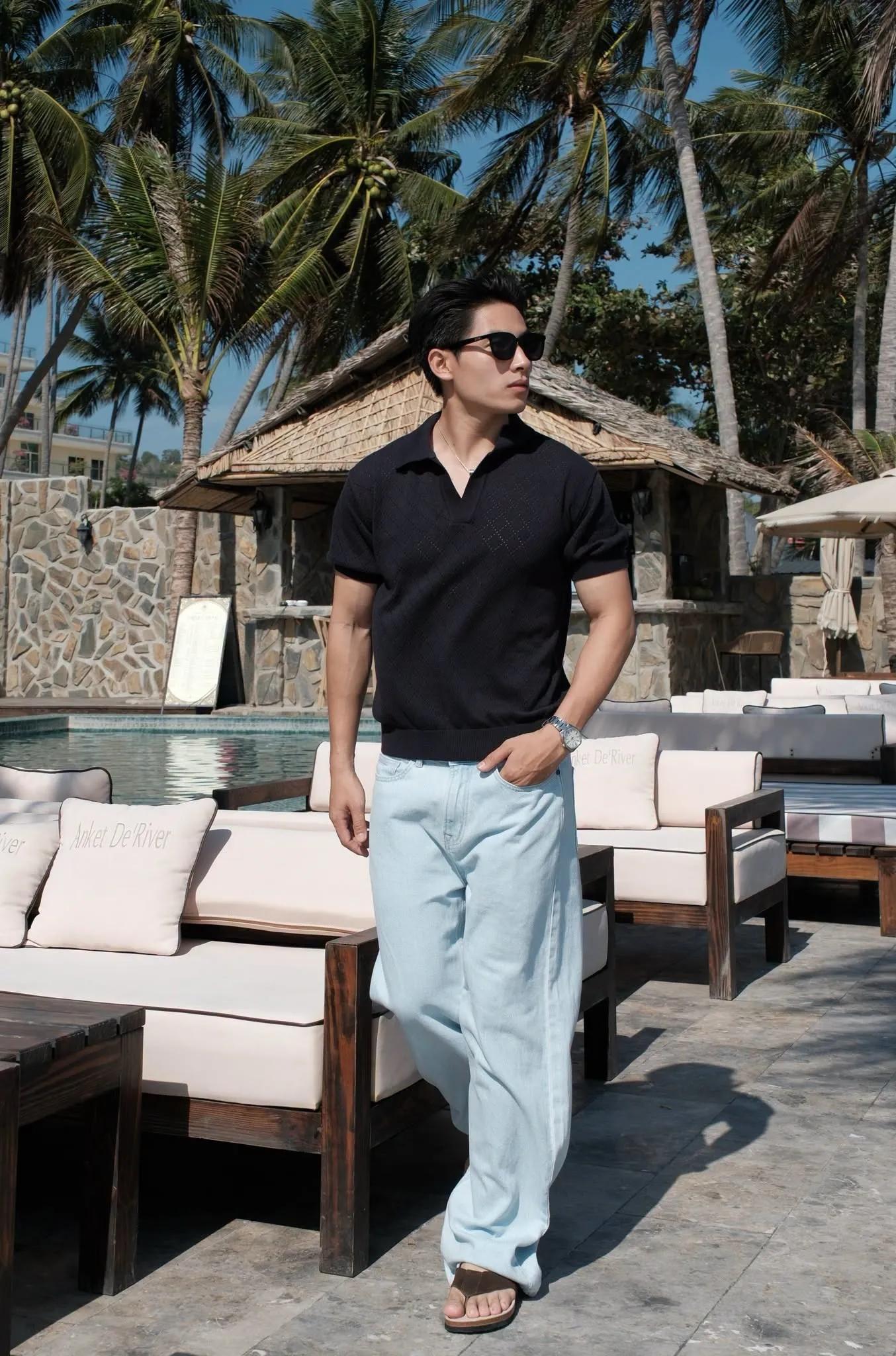 Outfit polo đen lịch lãm cùng jeans xanh sáng ống rộng tại khu nghỉ dưỡng